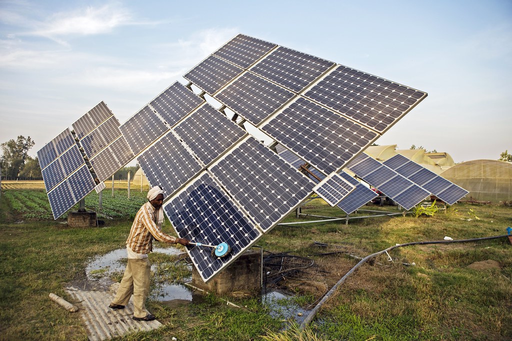 Farm worker clean the solar panels of a solar water pump at the farm